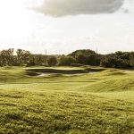 Panoramic view of a lush green golf course at Southern Oaks Championship Golf Course. Smooth