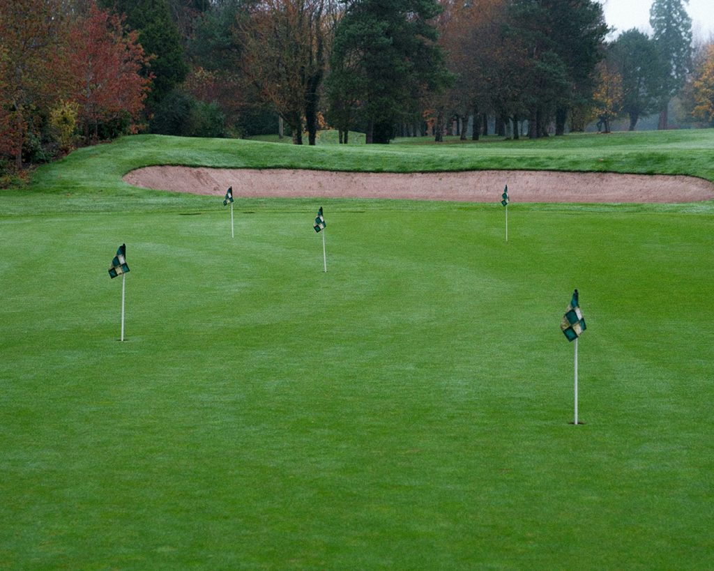 Panoramic view of a lush green golf course at The Tee Box - Golf Bar & Restaurant. Smooth
