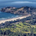 Panoramic view of a lush green golf course at Agate Beach Golf Course. Smooth
