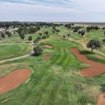 Panoramic view of a lush green golf course at Andrews County Golf Course. Smooth