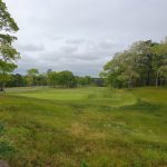 Panoramic view of a lush green golf course at Bayberry Hills Golf Course. Smooth
