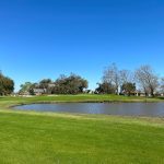 Panoramic view of a lush green golf course at Cane Row Golf & Turf Club. Smooth