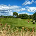 Panoramic view of a lush green golf course at Chris Bargas Golf Club at Whitney Farms. Smooth