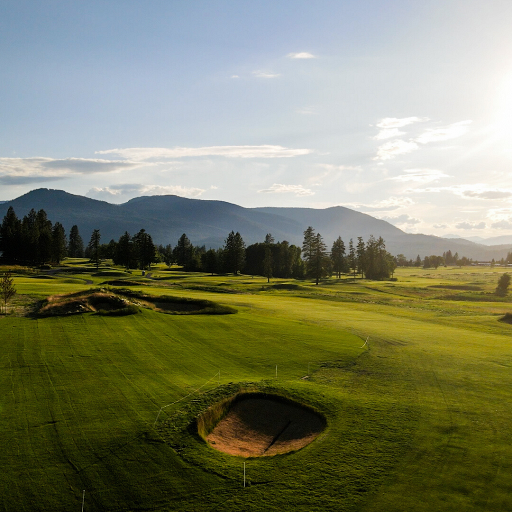 Panoramic view of a lush green golf course at Colville's Dominion Meadows. Smooth