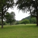 Panoramic view of a lush green golf course at Coonskin Golf Course. Smooth