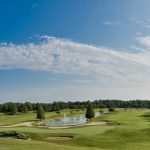 Panoramic view of a lush green golf course at Covered Bridge Golf Club. Smooth