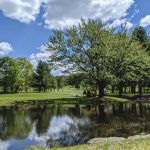 Panoramic view of a lush green golf course at Crestbrook Golf Course. Smooth