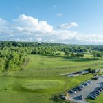 Panoramic view of a lush green golf course at Different Strokes Golf Center. Smooth