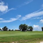 Panoramic view of a lush green golf course at Eagle's Nest Golf Course. Smooth