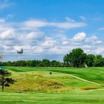 Panoramic view of a lush green golf course at Ellsworth Golf Course. Smooth