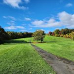 Panoramic view of a lush green golf course at Far Corner Golf. Smooth