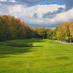 Panoramic view of a lush green golf course at Frye Island Golf Club. Smooth