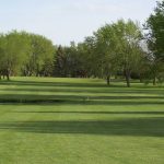 Panoramic view of a lush green golf course at Gates Park Golf Course. Smooth