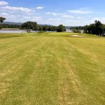 Panoramic view of a lush green golf course at Goose Pond Colony Lake Course. Smooth