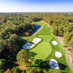 Panoramic view of a lush green golf course at Harbor Pines Golf Club. Smooth