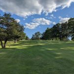 Panoramic view of a lush green golf course at Harrisville Golf Course. Smooth