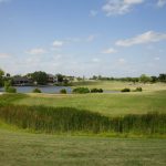 Panoramic view of a lush green golf course at Hidden Falls Golf Club. Smooth