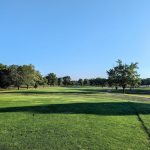 Panoramic view of a lush green golf course at Knolls Golf Course. Smooth