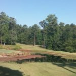 Panoramic view of a lush green golf course at Legacy Golf Links & Driving Range. Smooth