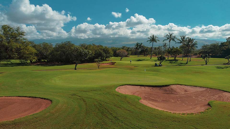 Panoramic view of a lush green golf course at Maui Nui Golf Club. Smooth