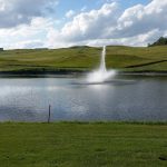 Panoramic view of a lush green golf course at Medicine Hole Golf Course. Smooth
