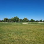 Panoramic view of a lush green golf course at Mountain Vista Greens Golf. Smooth