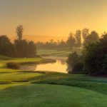 Panoramic view of a lush green golf course at Oak Creek Golf Club and Driving Range. Smooth