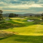 Panoramic view of a lush green golf course at Ozarks National Golf Course. Smooth