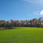 Panoramic view of a lush green golf course at Pebble Creek Golf Club. Smooth