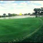 Panoramic view of a lush green golf course at Pine Bay Golf Course. Smooth