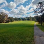 Panoramic view of a lush green golf course at Pine Ridge Golf Course. Smooth