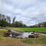 Panoramic view of a lush green golf course at RTJ Golf Trail at Grand National. Smooth