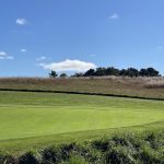 Panoramic view of a lush green golf course at Royal and Ancient Chappaquiddick Links. Smooth