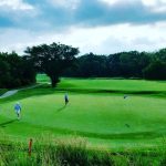 Panoramic view of a lush green golf course at Sand Creek Station Golf Course. Smooth
