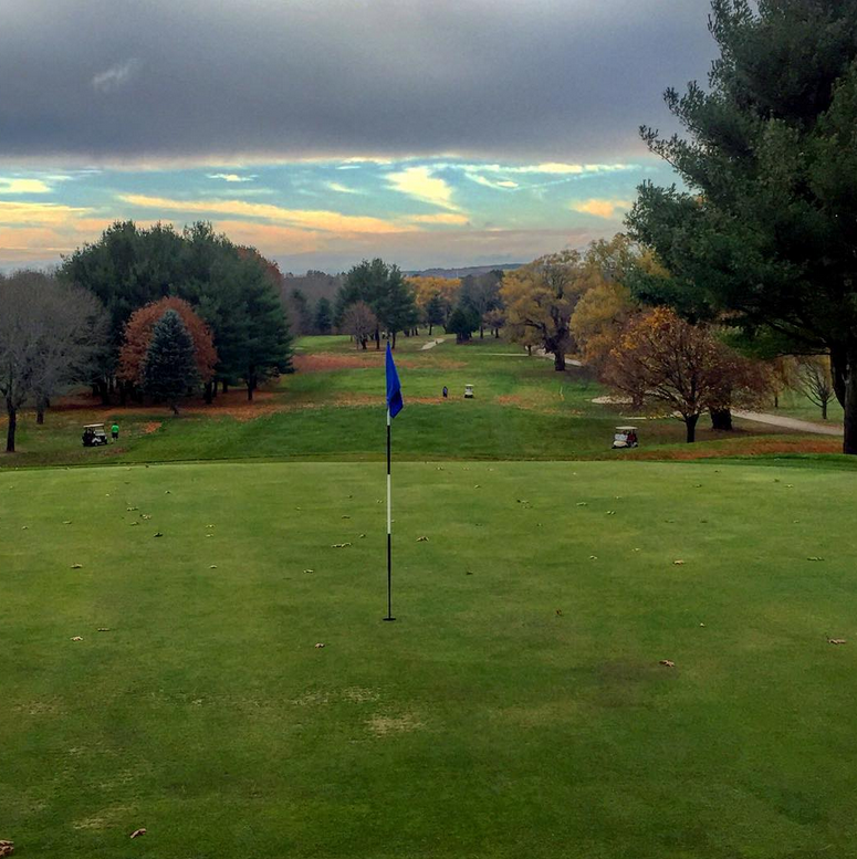 Panoramic view of a lush green golf course at Sandy Burr Country Club. Smooth