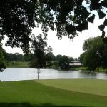 Panoramic view of a lush green golf course at Spring Creek Golf Course. Smooth