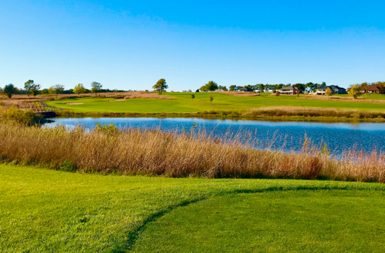 Panoramic view of a lush green golf course at Spring Creek Golf Course. Smooth