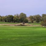 Panoramic view of a lush green golf course at Sugar Creek Golf Course. Smooth