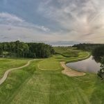 Panoramic view of a lush green golf course at Swan Point Yacht & Country Club. Smooth