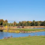 Panoramic view of a lush green golf course at Sweetgrass Golf Club. Smooth