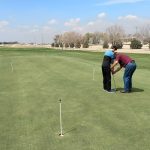 Panoramic view of a lush green golf course at Tamarisk Golf Course. Smooth