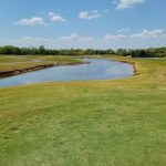 Panoramic view of a lush green golf course at Ted Rhodes Golf Course. Smooth