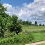 Panoramic view of a lush green golf course at The Emerald Golf Course. Smooth