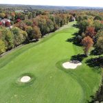 Panoramic view of a lush green golf course at The Golf Club at Oxford Greens. Smooth