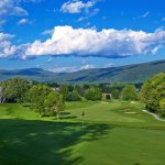 Panoramic view of a lush green golf course at The Golf Club at The Equinox. Smooth
