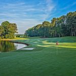 Panoramic view of a lush green golf course at The Golf Club of Georgia. Smooth