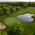 Panoramic view of a lush green golf course at The Grizzly Golf and Social Lodge. Smooth