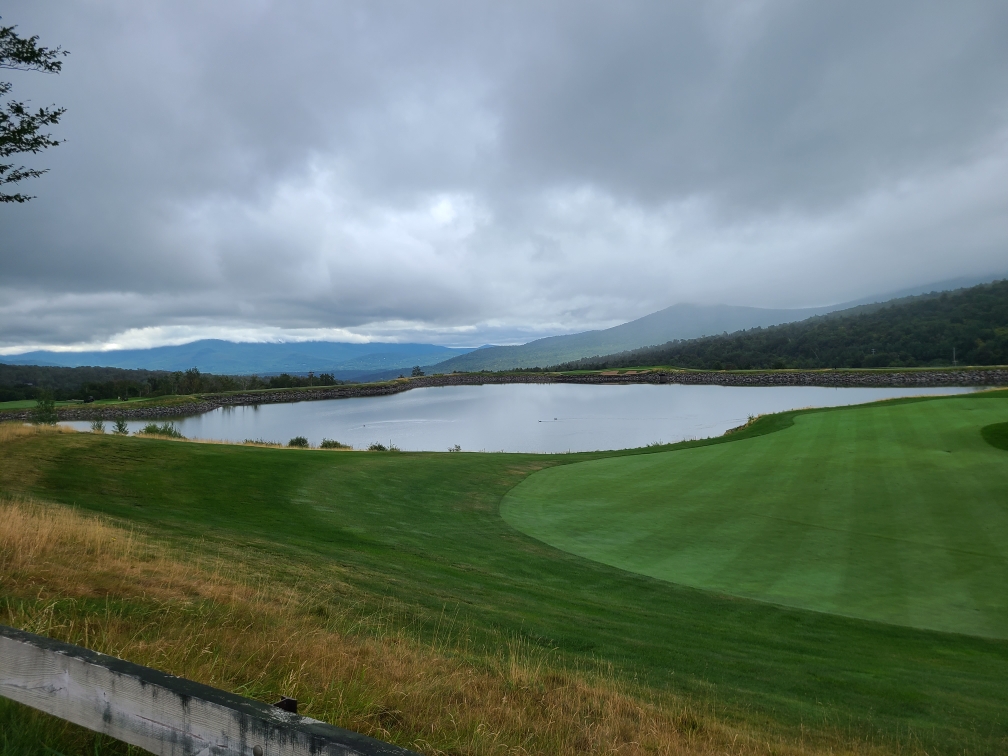 Panoramic view of a lush green golf course at The Mountain Course at Spruce Peak. Smooth