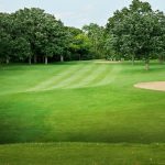 Panoramic view of a lush green golf course at Twin Lakes Country Club. Smooth