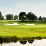 Panoramic view of a lush green golf course at Twin Lakes Golf Course. Smooth